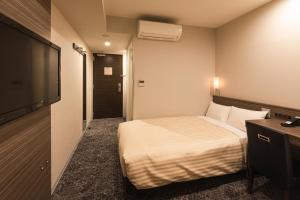 a hotel room with a bed and a flat screen tv at Sotetsu Fresa Inn Shimbashi Hibiyaguchi in Tokyo