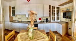 a kitchen with white cabinets and a table with a vase at Flowery House in Miglianico