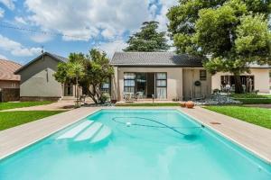 a large blue swimming pool in front of a house at Siesta Guest House in Alberton
