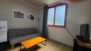 a living room with a couch and a table and a window at Bella Yuna Inn in Jeju