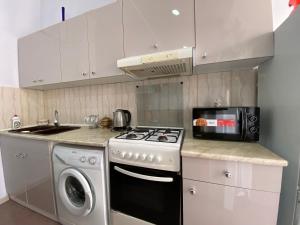 cocina blanca con fogones y microondas en Apartment On Luka Asatiani 2 en Batumi