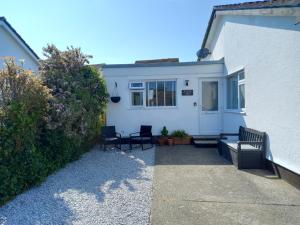 a white house with two chairs and a patio at Ruby's Den in Carbis Bay