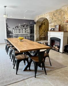 uma sala de jantar com uma mesa e cadeiras e uma lareira em A l'Ombre d'Azay - Demeure d'Hôtes em Azay-le-Rideau