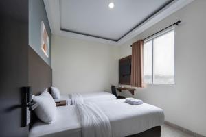 a hotel room with two beds and a window at Cove West Inn Cihampelas in Bandung