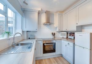 a kitchen with white cabinets and a sink at Seashell Cottage in Whitby