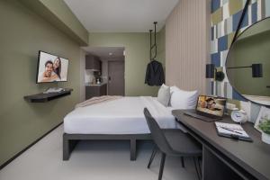 a hotel room with a bed and a desk and a mirror at The Suites at Torre Lorenzo Malate - Managed by The Ascott Limited in Manila