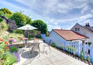 une terrasse avec un parasol, une table et des chaises dans l'établissement Seals Cottage, à Whitby