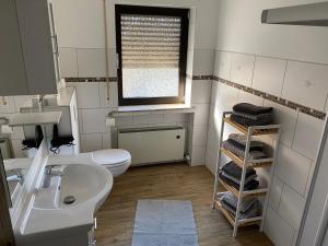 un bagno con lavandino, WC e finestra di Ferienwohnung Anne a Eppenrod