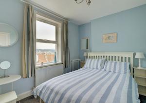 - une chambre bleue avec un lit et une fenêtre dans l'établissement Seals Cottage, à Whitby