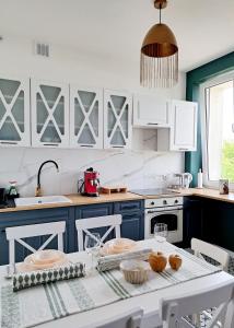 una cocina con armarios azules y blancos y una mesa. en Greener Apartament en Kielce