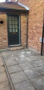 a brick building with a black door and a sidewalk at Dorcas Lodge - Lovely 5 Bedroom home with free parking and Wi-Fi in Nevendon