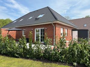 ein rotes Backsteinhaus mit vielen Büschen in der Unterkunft Landhaus Seewind mit Sauna in Dornum