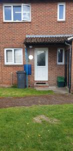 a red brick house with a white door and a green yard at Lovely flat with Wi-Fi and free parking in Reading