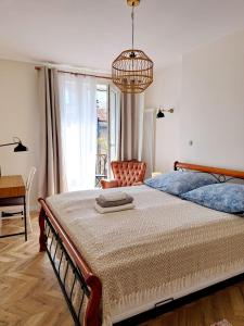 1 dormitorio con 1 cama grande y lámpara de araña en Greener Apartament en Kielce