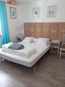 un grande letto con lenzuola e cuscini bianchi in una camera da letto di Laissez-vous séduire a Grand-Village-Plage