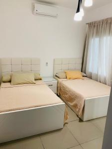 Duas camas num quarto com paredes brancas em Lovely chalet 4- bedroom directly on the lagoon em El Alamein