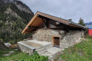 a small stone building with a wooden roof and stairs at Chalet 1829 in Sainte-Foy-Tarentaise