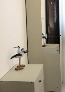 Una estatua de pájaro sobre una mesa frente a un espejo. en Charming Apartment- Peniche, en Consolacao
