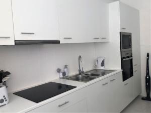Una cocina blanca con fregadero y microondas. en Charming Apartment- Peniche, en Consolacao