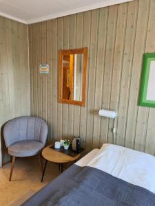 ein Schlafzimmer mit einem Bett, einem Stuhl und einem Tisch in der Unterkunft Berlevåg Motell AS in Berlevåg