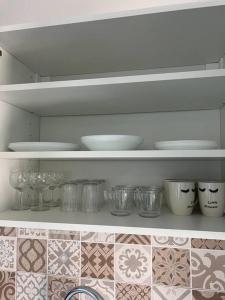 a kitchen shelf with bowls and dishes on it at Appartement Crème in Manosque