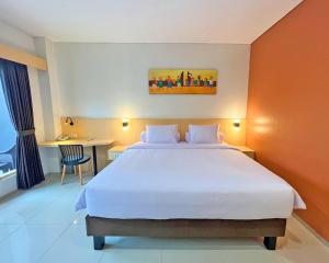 um quarto com uma grande cama branca e uma secretária em Asyana Sentul Bogor em Bogor