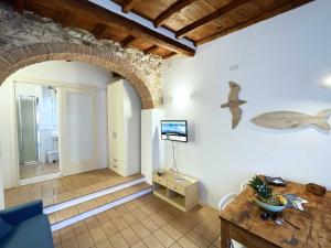 a living room with an arch with a television and a table at Casa Cotone - Monolocale in Marciana Marina