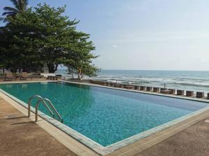 een zwembad naast een strand met de oceaan bij Khanom Golden Beach Hotel in Khanom