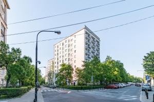 a tall white building on a city street with cars at Wałowa 4 by Homeprime in Warsaw