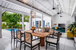 an open dining room with a wooden table and chairs at The Beach House in Canggu