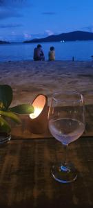 a glass of wine sitting on a table at the beach at REFUGIO na frente do mar em Ilha de Araujo in Paraty