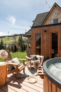 a dog sitting on a deck next to a hot tub at Domki w Białce WOODHOUSE- basen, sauna, jacuzzi in Białka Tatrzańska