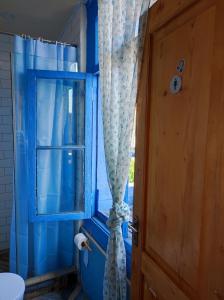 a blue bathroom with a window and a curtain at Hostel ERA in Tbilisi City