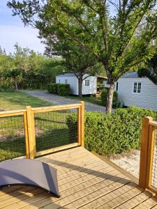 een houten terras met een hek in een tuin bij Camping Beaussement LIBERTY climatisé in Chauzon