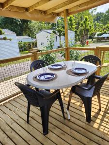 une table et des chaises sur une terrasse en bois dans l'établissement Camping Beaussement LIBERTY climatisé, à Chauzon