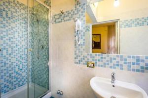 フィレンツェにあるホテル アルカディアの青いタイル張りのバスルーム(シンク、シャワー付)