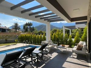 a patio with chairs and a pool with a view at Villa Marina 4+1 Camuva in Kemer