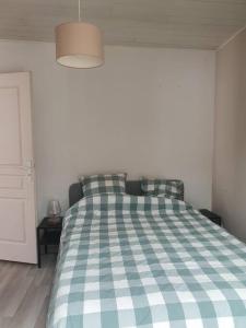 a bed with a checkered blanket in a bedroom at Appartement sur cour privative in Capbreton