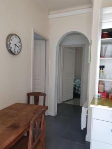 a kitchen with a table and a clock on the wall at Appartement sur cour privative in Capbreton