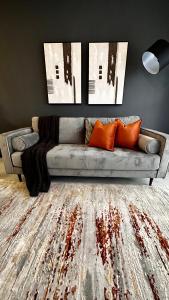 a living room with a gray couch with orange pillows at Stylish Executive Apartment with Power Backup in Johannesburg