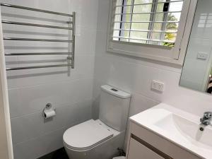 a white bathroom with a toilet and a sink at Tequila Sunset Waterfront in Sanctuary Point