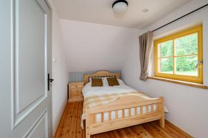 1 dormitorio con cama de madera y ventana en Osada Biały Wilk domek "Żółty", en Przysłup