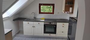 a kitchen with white cabinets and a sink and a window at Gyöngyike Apartmanház Vonyarcvashegy in Vonyarcvashegy