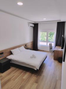 um quarto com uma cama, uma secretária e uma janela em H.T Hotel em Belgrado