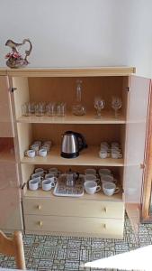 a wooden cabinet with a tea pot and dishes at appartamento Walter in centro in Rosolina Mare