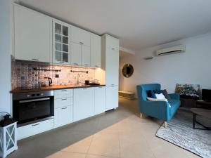 eine Küche mit weißen Schränken und einem blauen Stuhl in der Unterkunft Oasis club apartments in Lozenets