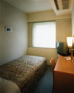 a bedroom with a bed and a desk and a television at Himeji Green Hotel Tatemachi in Himeji