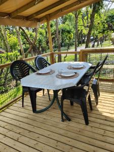 a table with four chairs on a wooden deck at Camping Beaussement SWEETY in Chauzon