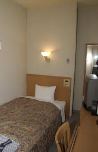 姫路市にある姫路グリーンホテル立町のベッドとデスクが備わるホテルルームです。