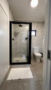 a bathroom with a glass shower and a toilet at Stylish Executive Apartment with Power Backup in Johannesburg